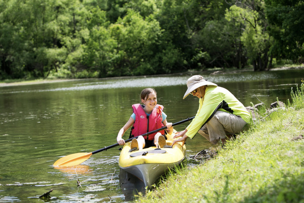 residents helps granddaughter into kayak